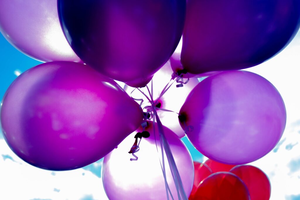 A bunch of purple balloons all tied together are shown from below.