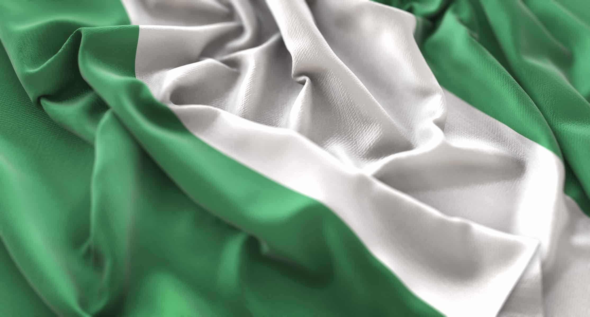 A green and white Nigerian flag is seen loosely crumpled on a flat surface.