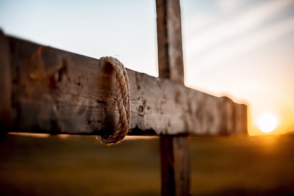 Selective focus shot of a hand made a wooden cross with rope wrapped around and blurred background