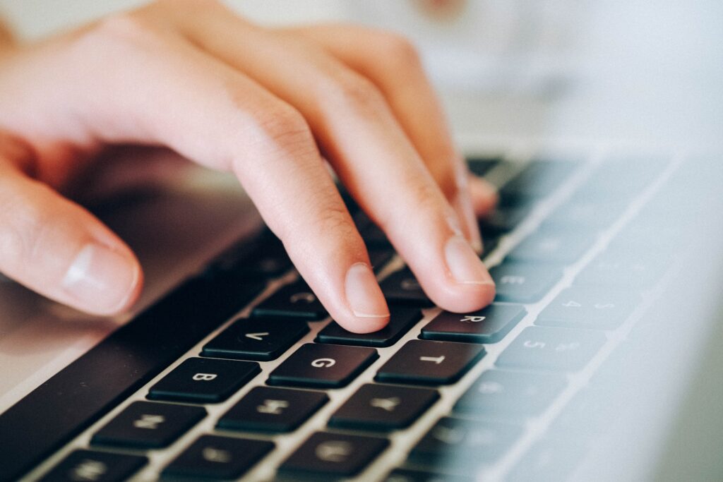 A man's hand is shown typing with one hand on a keyboard.