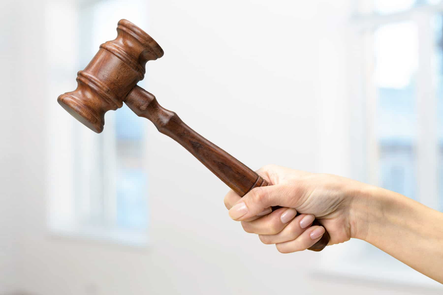 A hand holds a gavel in mid-air.