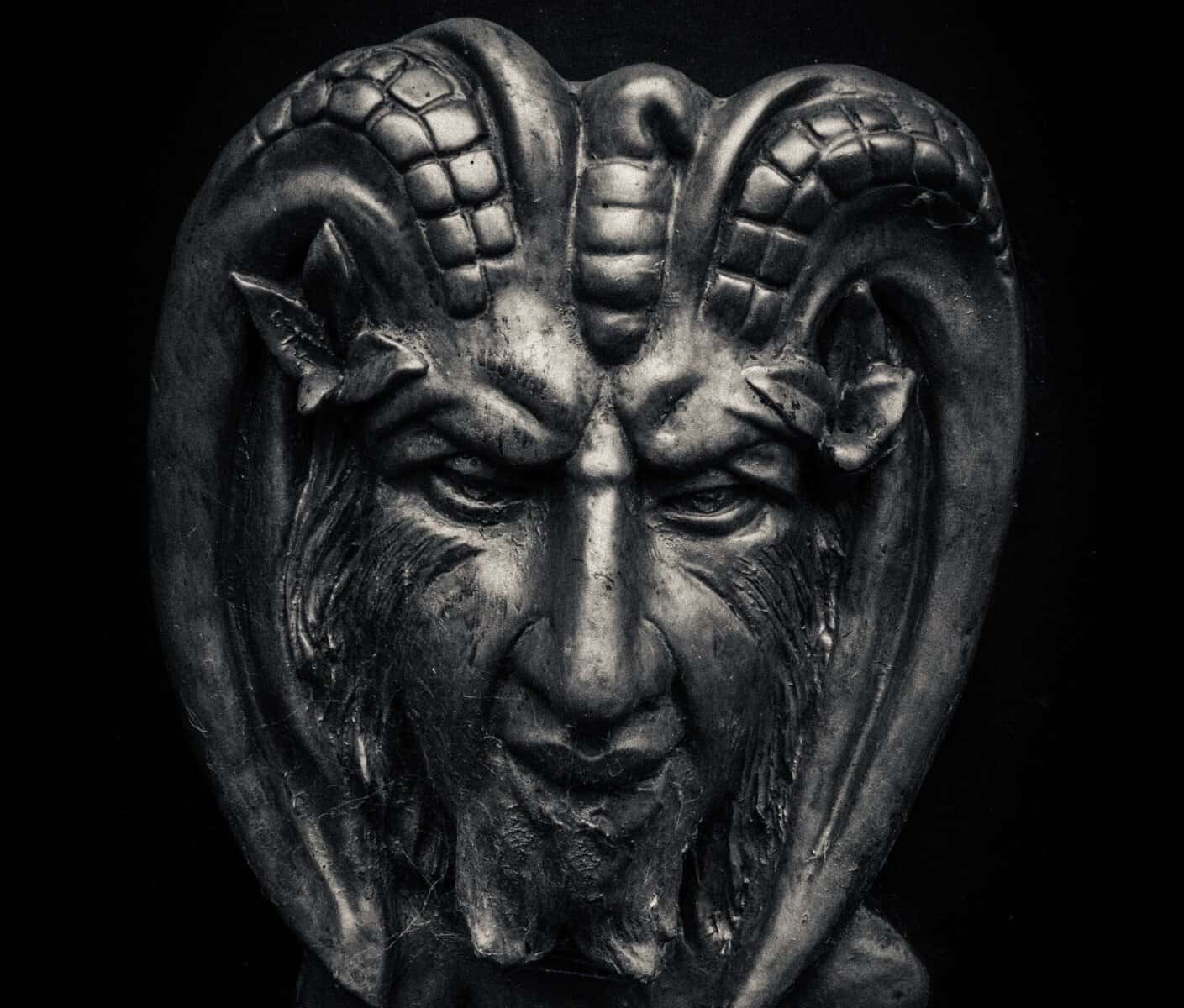 The face of a devil statue with ram horn is shown.