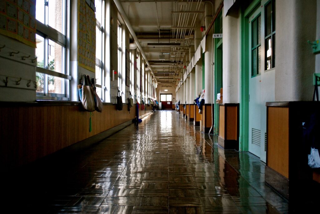 A school hallway is shown lined with hanging backpacks.
