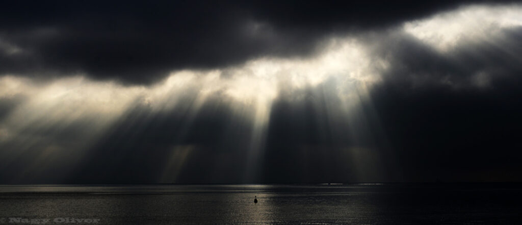 Sun is seen shining through a line of very dark clouds.