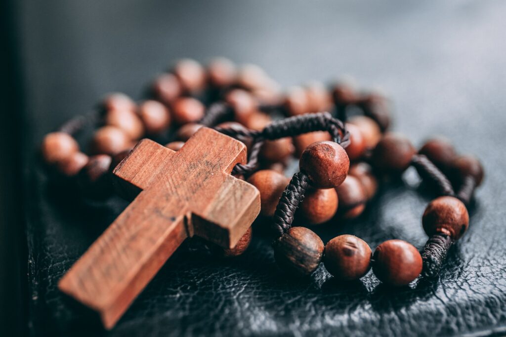 A wooden rosary is shown close up in soft light.