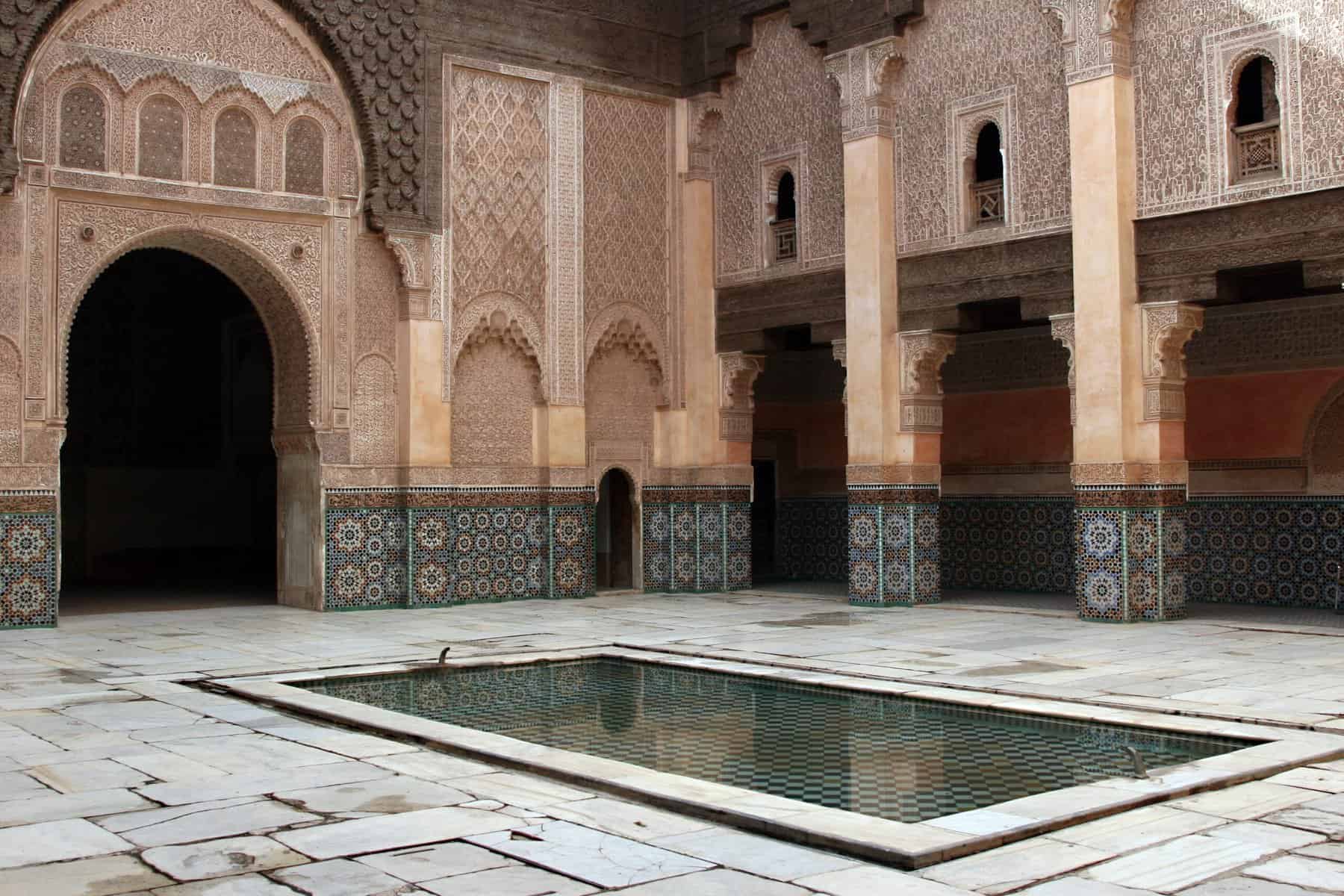A pool in the Ben Youssef Mosque in Morocco is shown with the mosque as the backdrop.