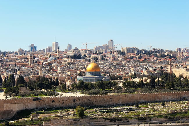A city skyline, perhaps Mideastern, is shown with a yellow domed mosque close to the camera.