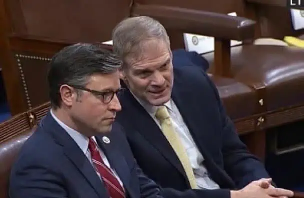 Mike Johnson is shown sitting in a congressional chamber next to and speaking with Jim Jordan.