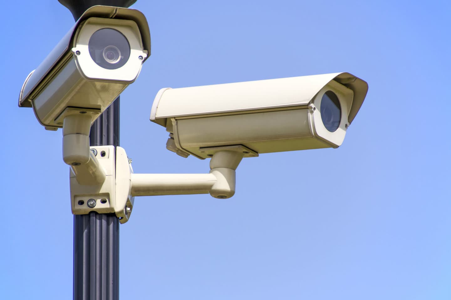 Surveillance cameras are shown mounted high on a pole.