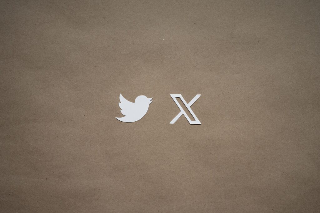 The old Twitter bird logo is placed next to the new 'X' logo on a brown paper bag background.