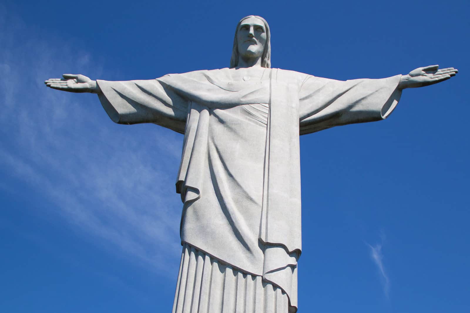 Brazil's Christ the Redeemer Statue is shown from below against a blue sky.