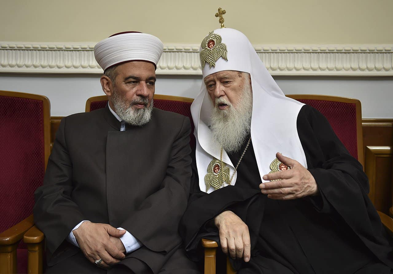 Mufti Ahmed Tamim and Patriarch Filaret, both of Ukraine, are shown seated and talking.
