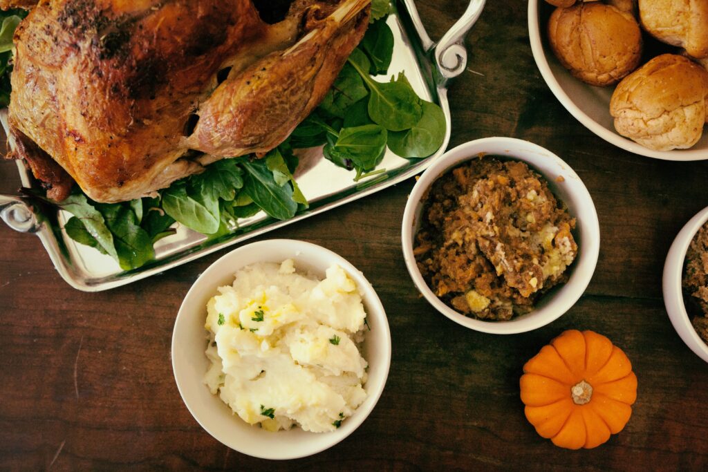Turkey, mashed potatoes, dressing and rolls are shown on a table.