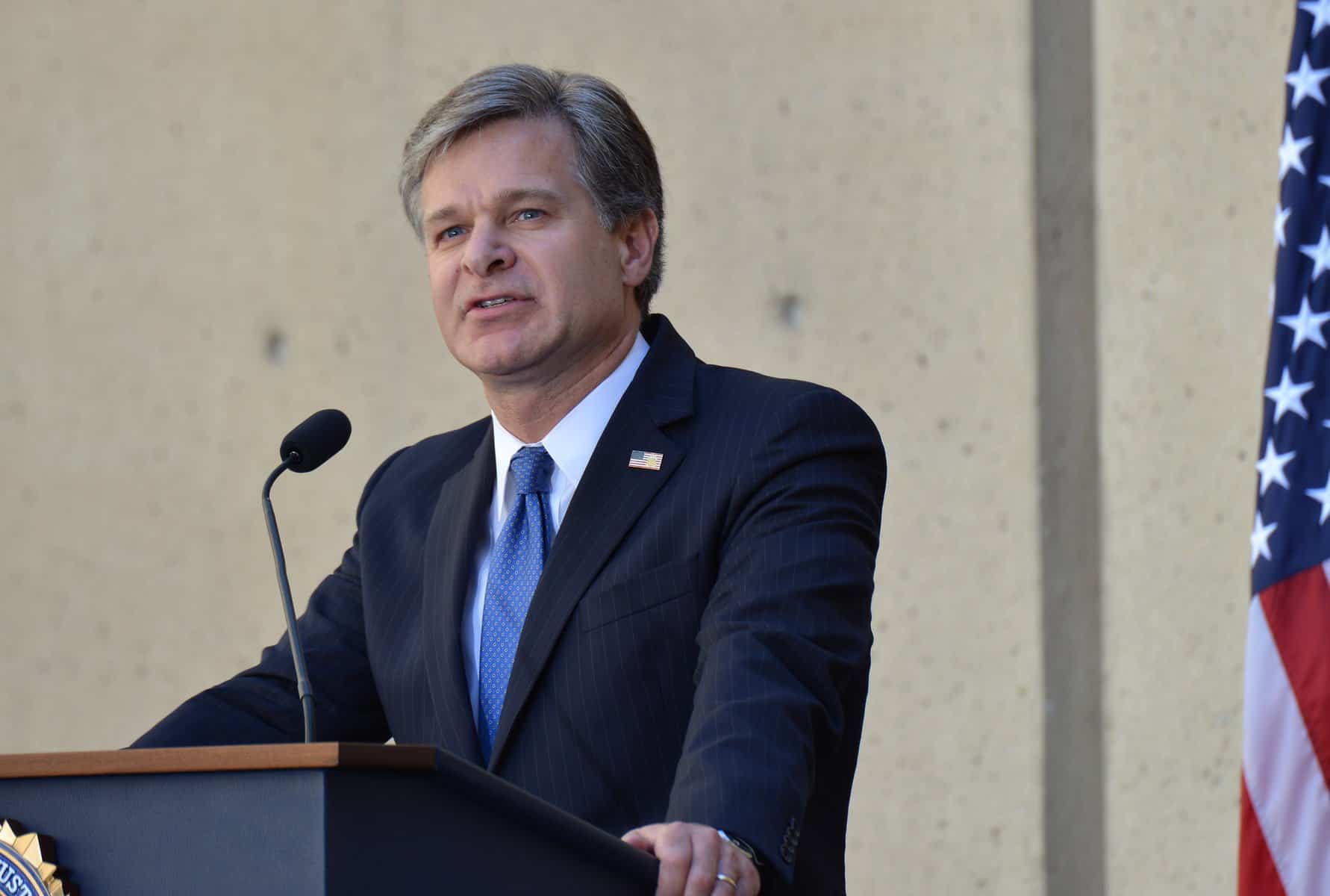 FBI Director Christopher Wray stands at a podium.