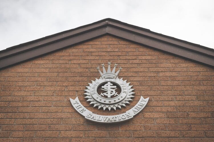 The Salvation Army emblem is seen on the peak of an orange brick building facade.