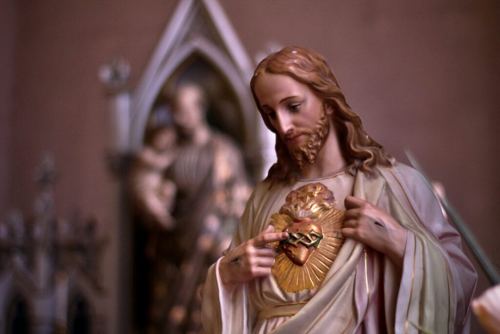 In statue form, Jesus is seen touching his heart with tunic pulled away.