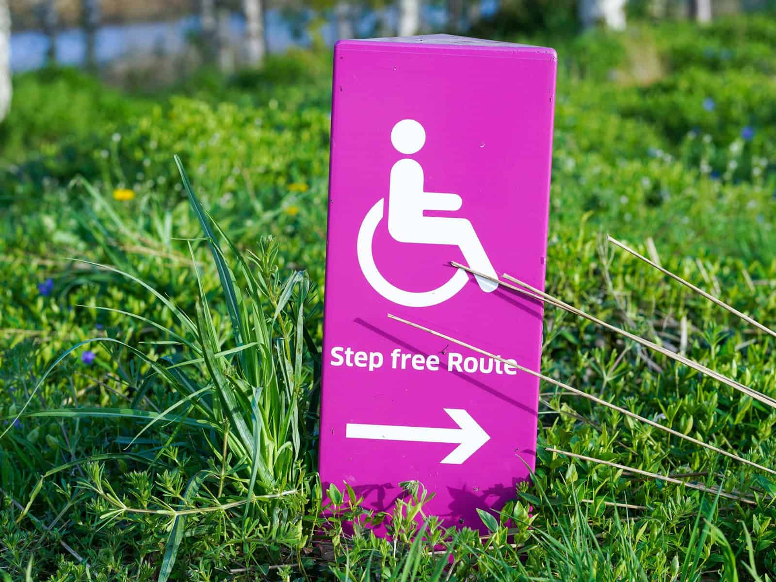 A bright pink sign shows a wheelchair graphic with the word "step free route' and an arrow.