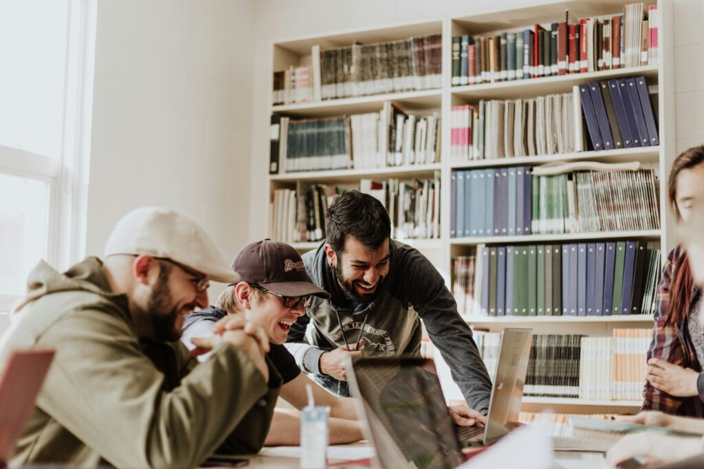 Demographic cliff and Christian colleges: A looming challenge Three men in a library looking at a laptop and laughing.