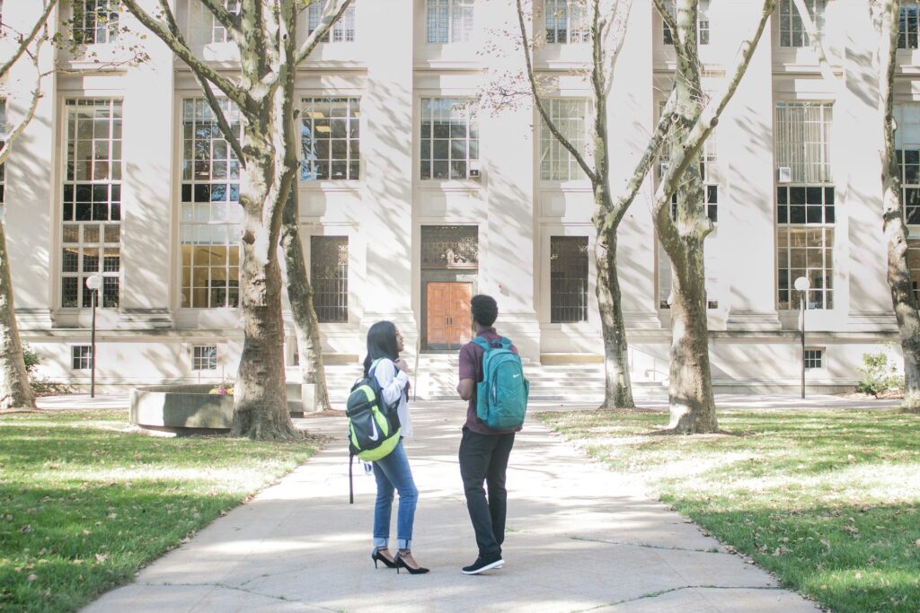 Judge sides with Christian colleges in Minnesota dual-credit program dispute A man and a woman with backpacks stand in front of a large stone building.