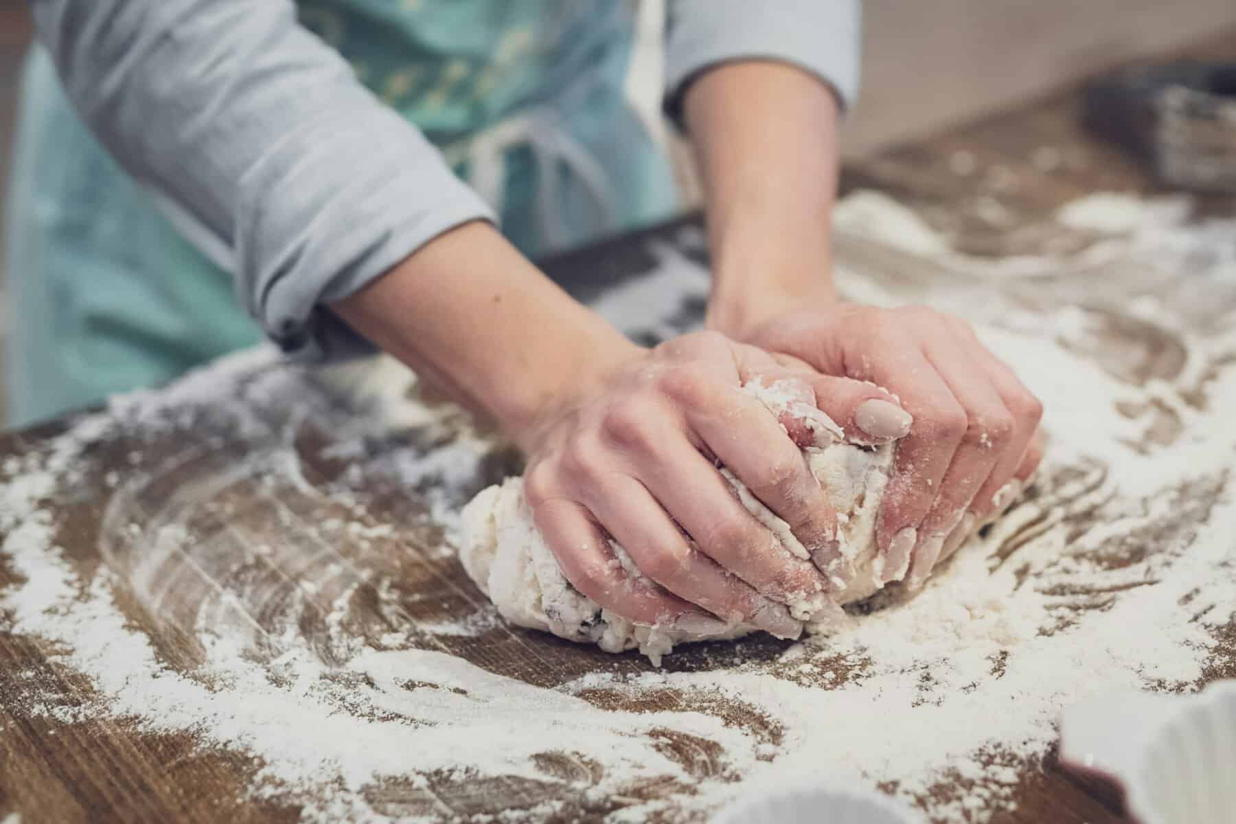 A woman with manicured nails kneading dough.
