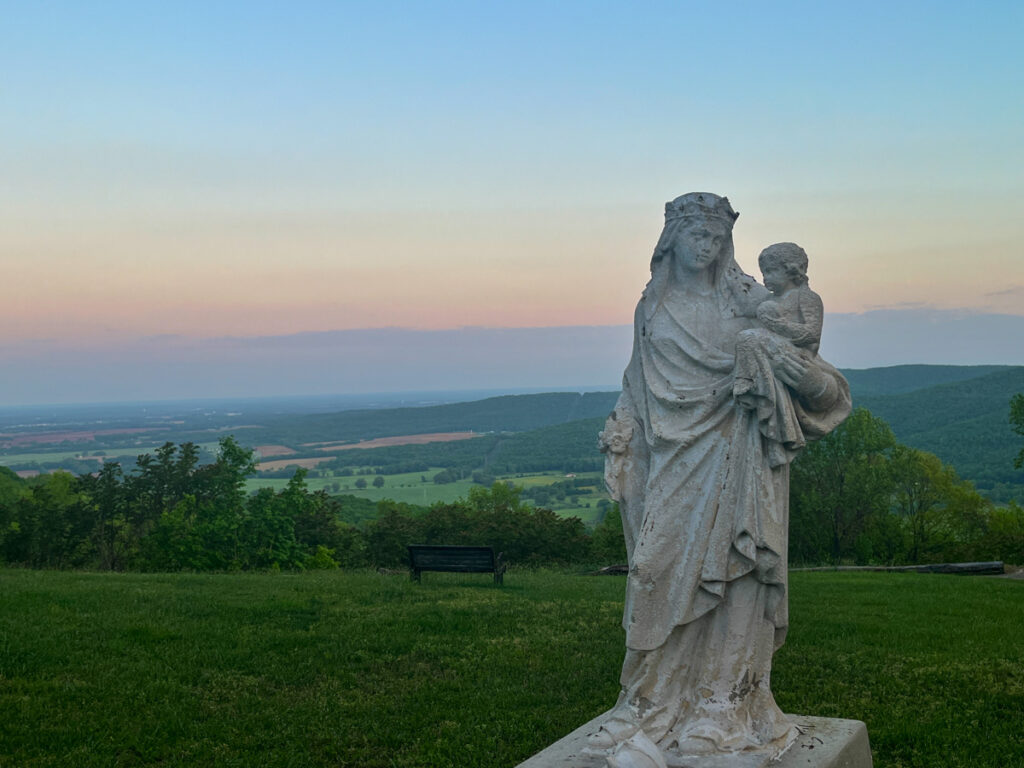Mary and the Christ child statue with a sunrise behind. St. Mary's Sewanee