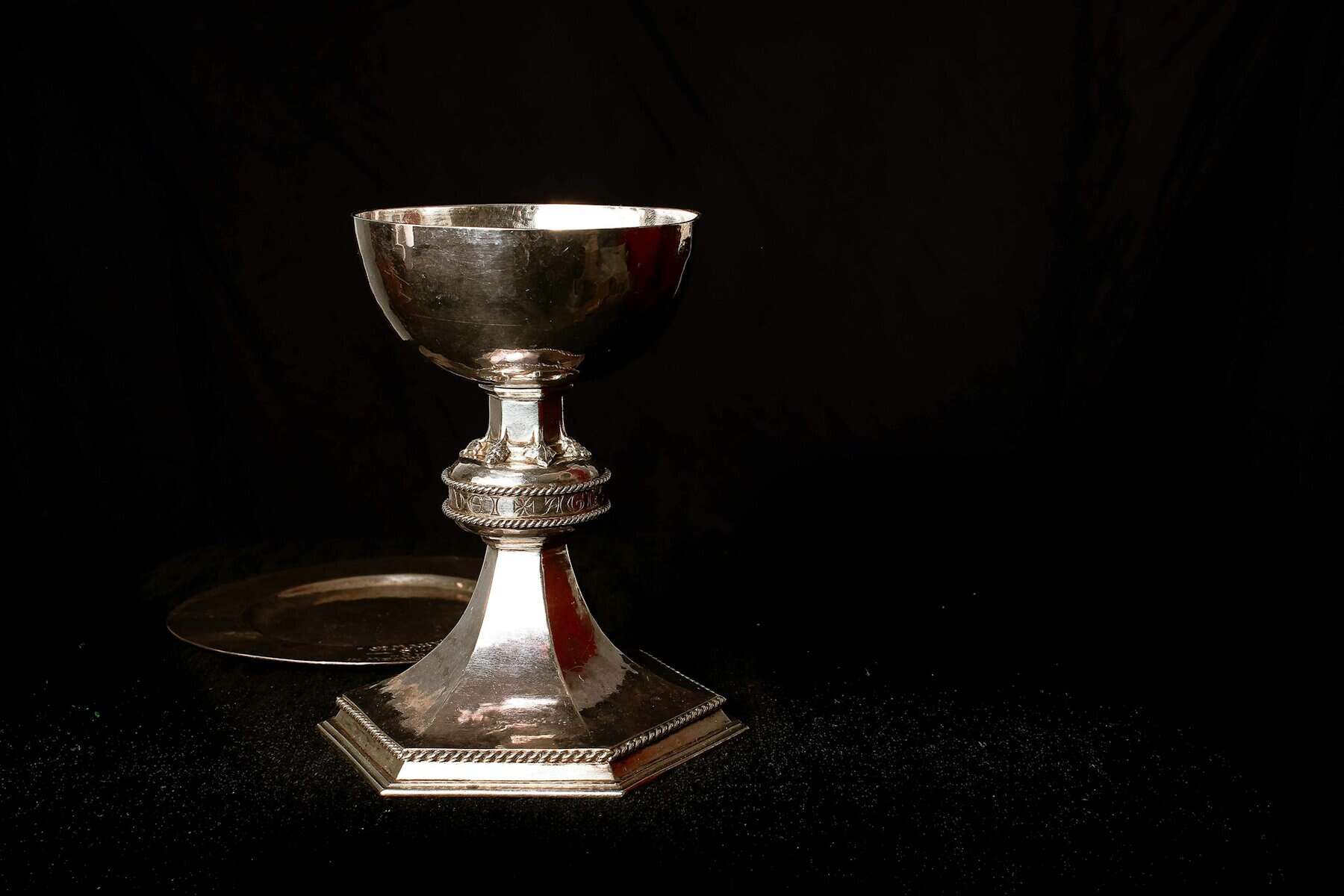 A silver chalice against a black background.