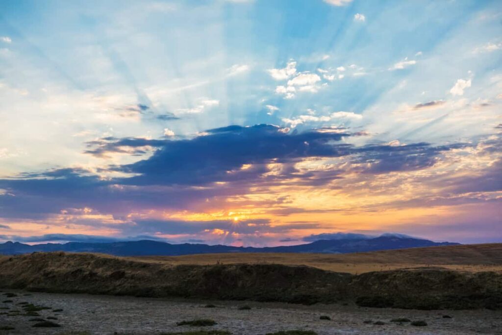 Alternative Facts vs. Eternal Truth (Hebrews 10:16) A sunset with clouds and God rays with mountains in the background and a dry creek bed in the foreground.