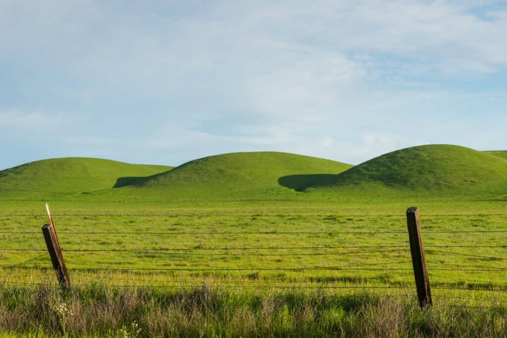Beyond Moving Mountains (Mark 11:24) View of green rolling hills with a blue cloudy sky.