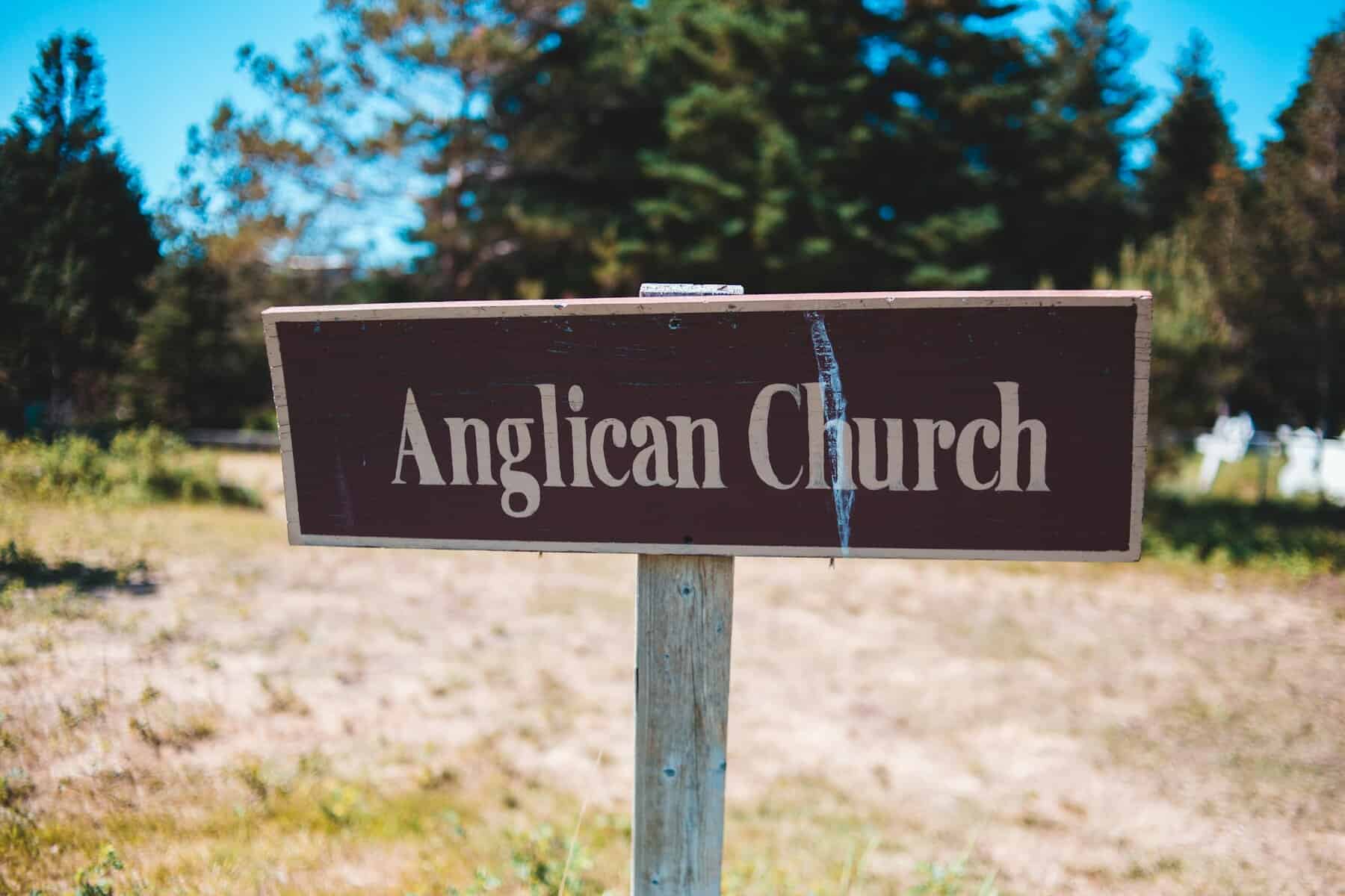 A nondescript brown sign with "Anglican Church" in white lettering.