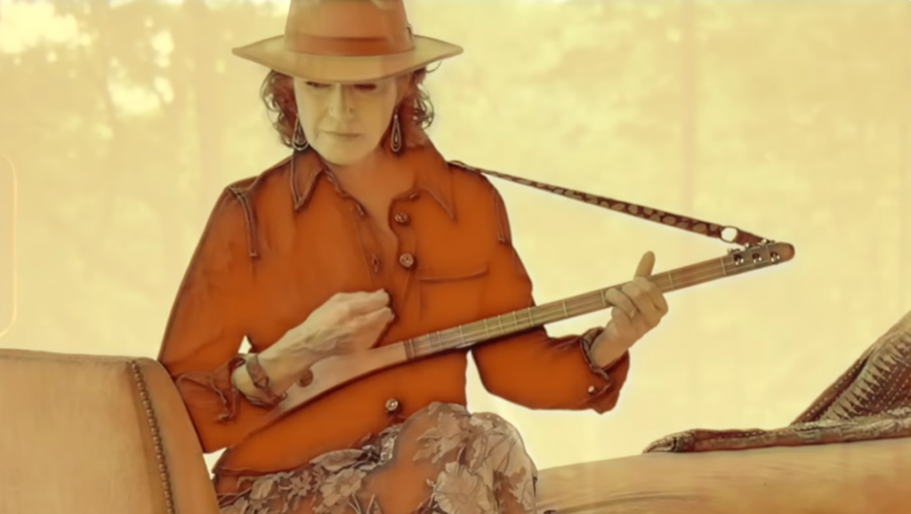 Amy Grant in western style dress playing the strumstick.