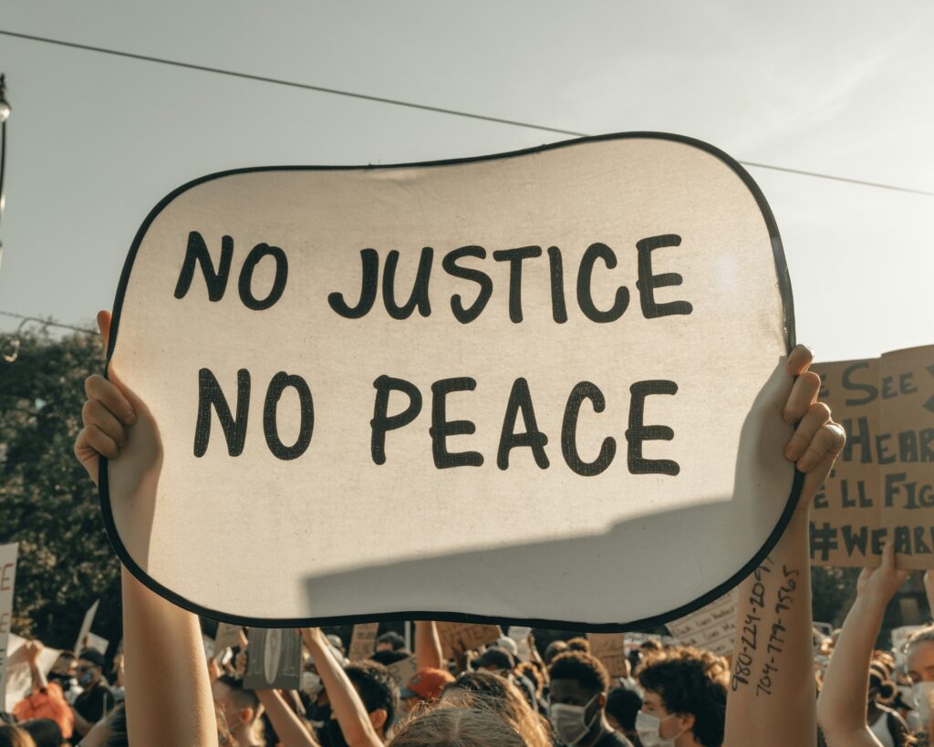 A protestor holds a sign saying No justice, no peace.