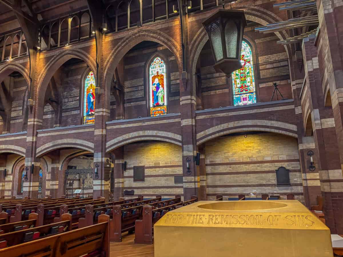 The inside of St. Paul's Episcopal Church, Chattanooga, TN showing pews, font, and stained glass.