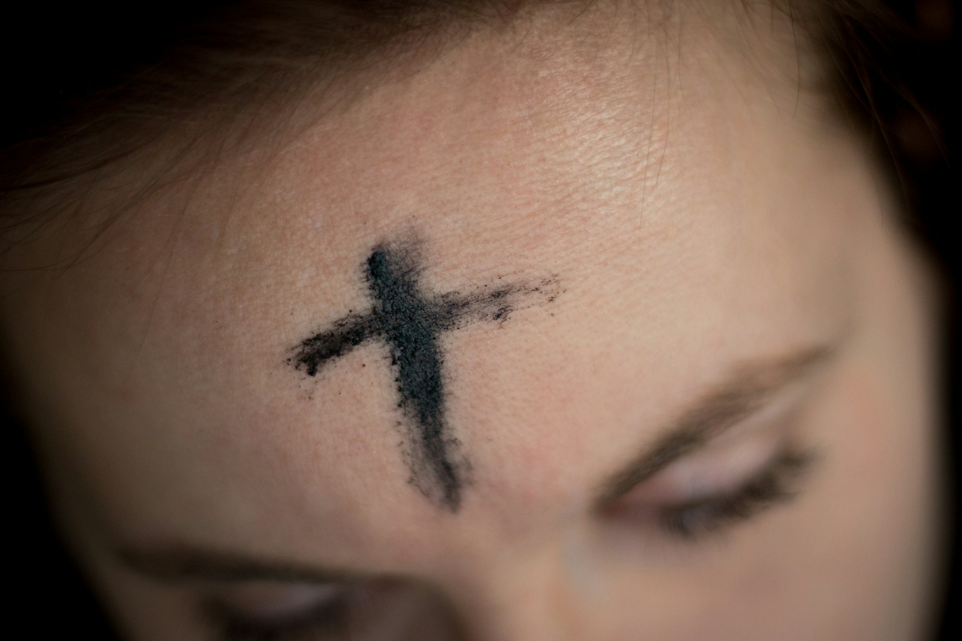 Close-up of a woman's forehead with an ash cross on it.