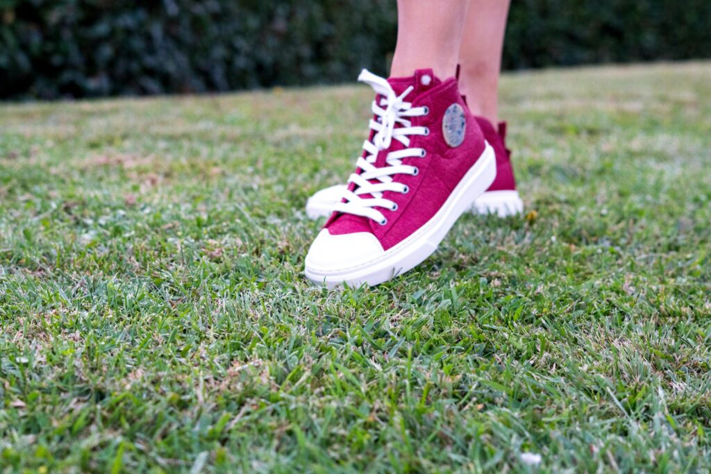 A woman's feet in bright red low top sneakers.