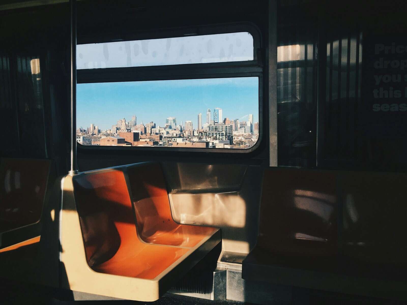 An image of seat on the NYC subway DQ train with Bay Ridge Brooklyn visible through the window.