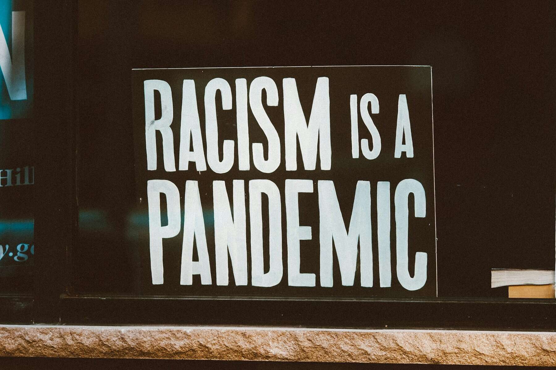 A sign says "racism is a pandemic."