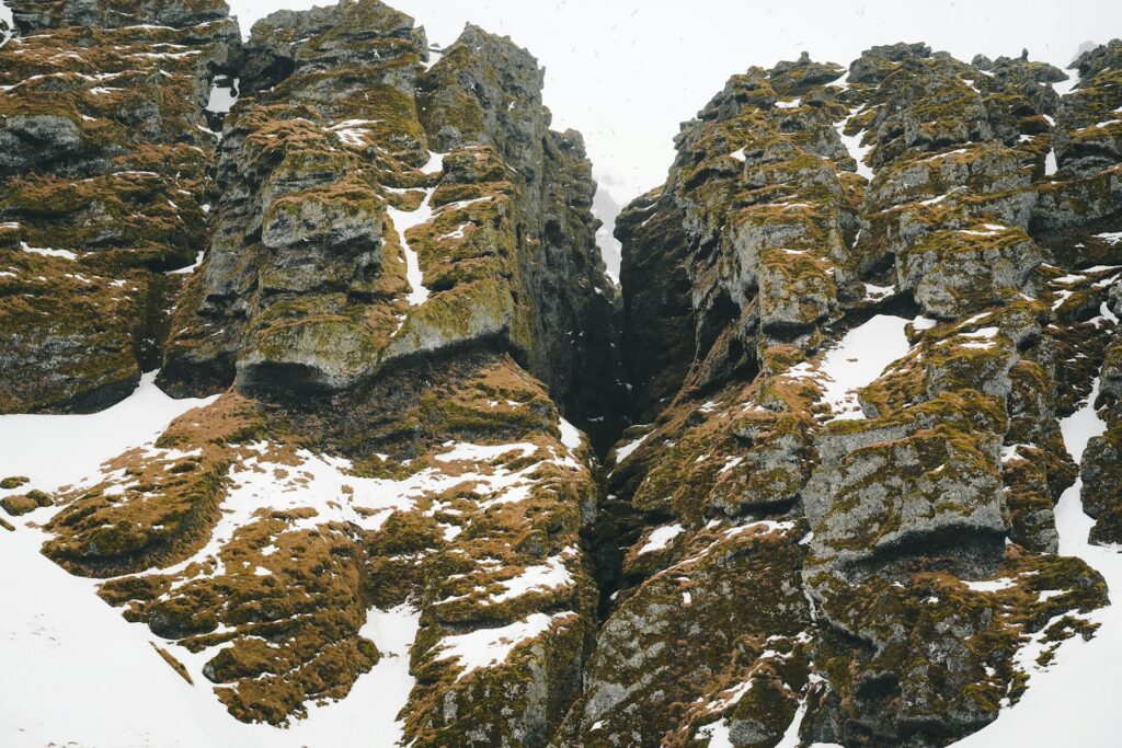 A fault line shown between two snow covered rock formations.