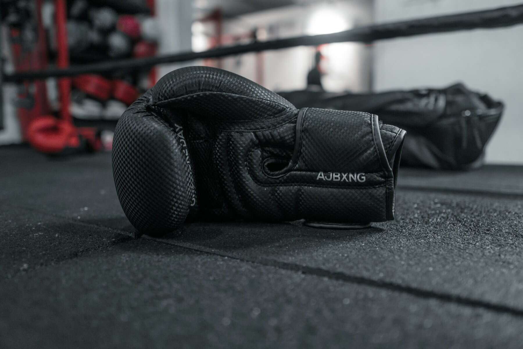 Black boxing gloves sitting in a boxing ring.