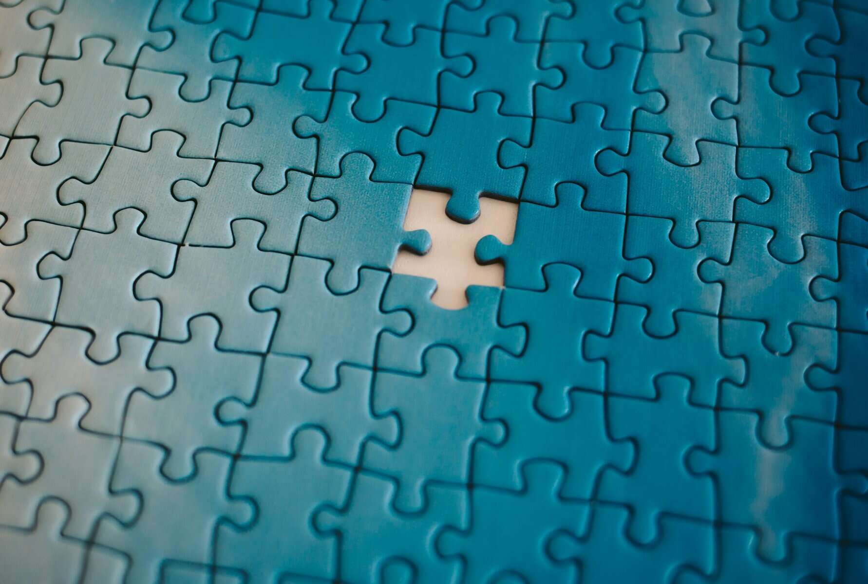 A blue puzzle with one missing piece.