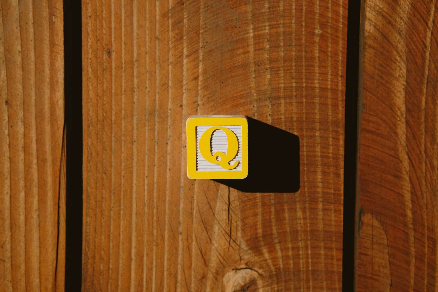 A child's wooden block with a Q on it.