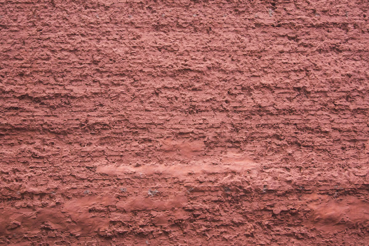 An old red weathered brick wall with thick mortar.