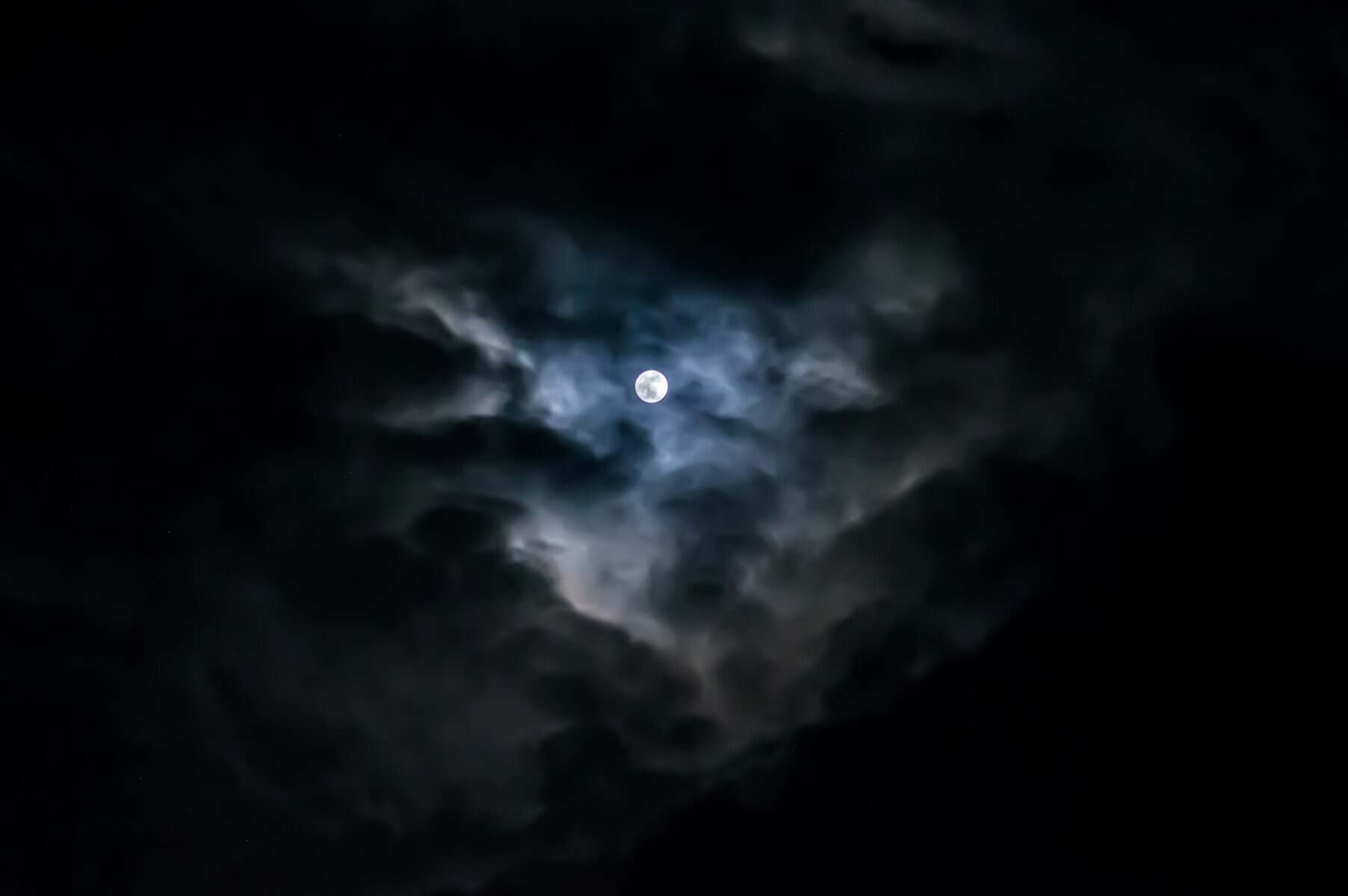 The moon seen through dark, ominous clouds.