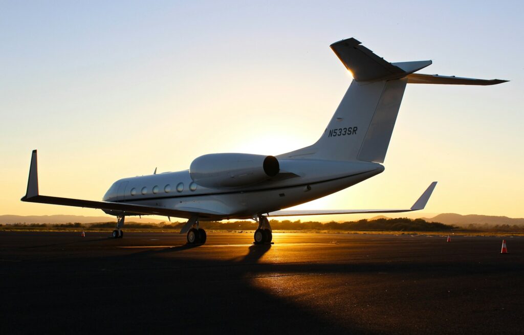 A private aircraft sits on a runway at sunset.