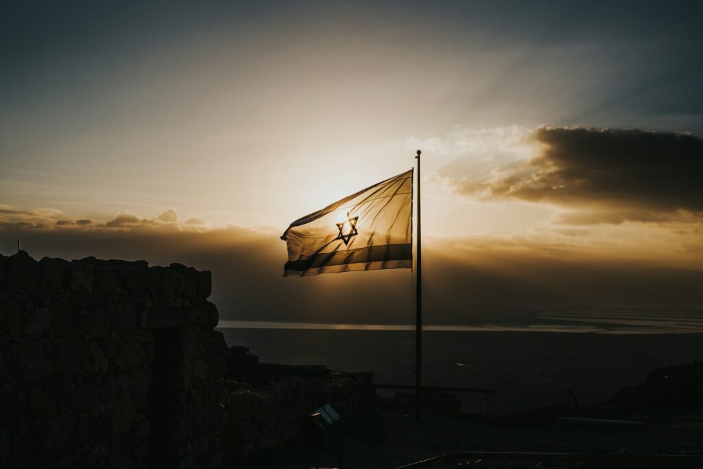 The flag of Israel with the sun behind it.