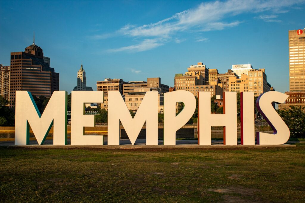 Huge white letters spell Memphis with the city behind them.