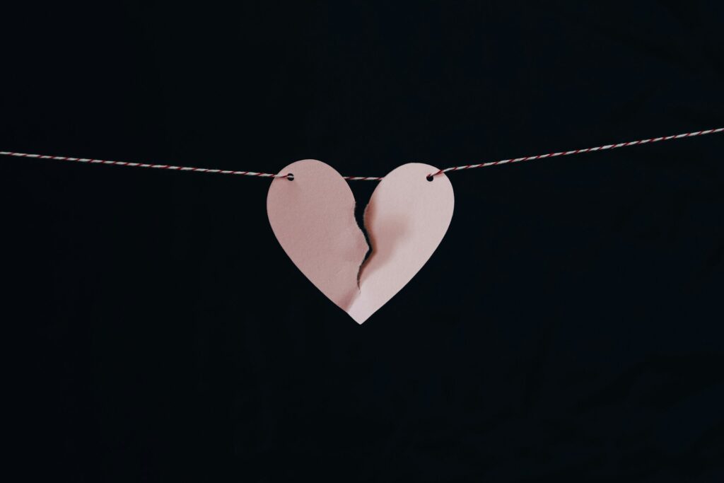 A torn pink paper heart hanging in a string.
