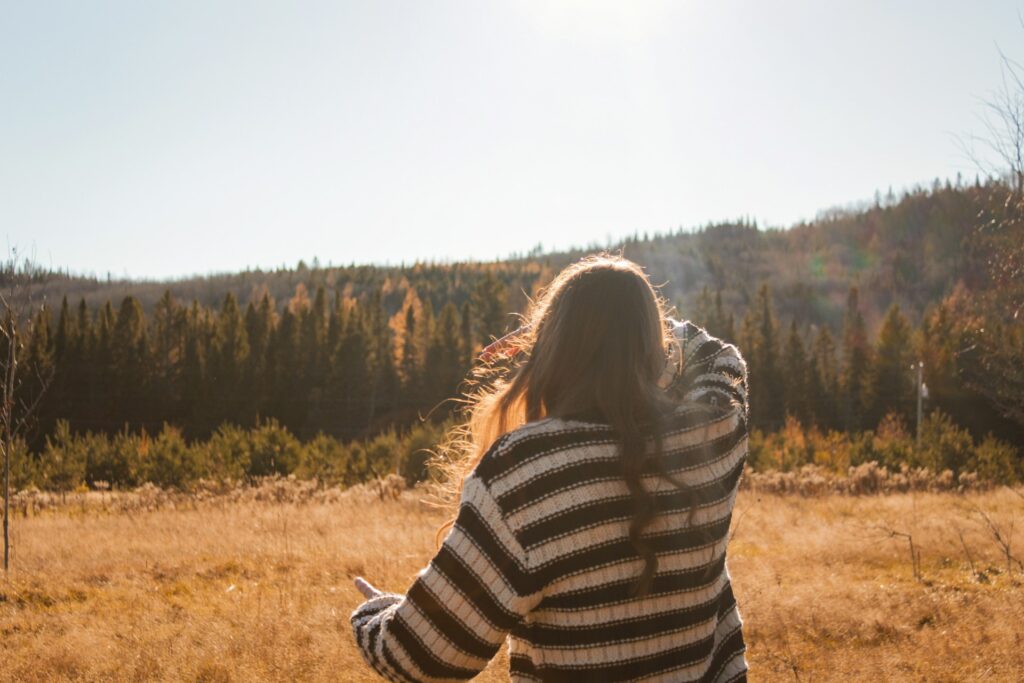 A woman in a field with her back to the camera.