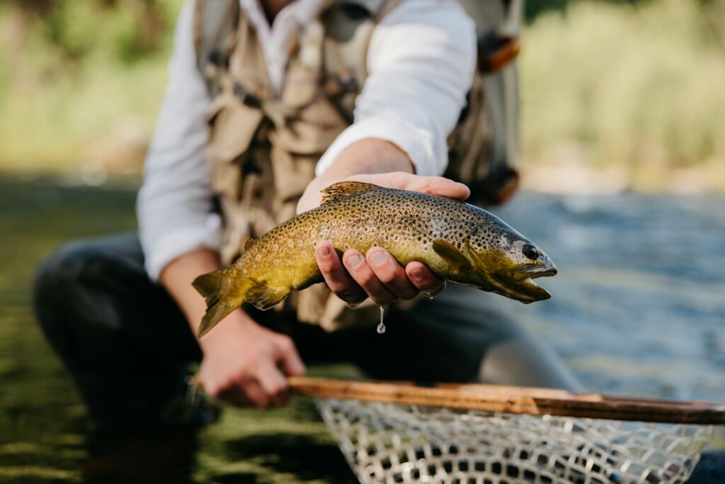 Let Jesus Clean the Fish A man holding a trout fish he just caught.