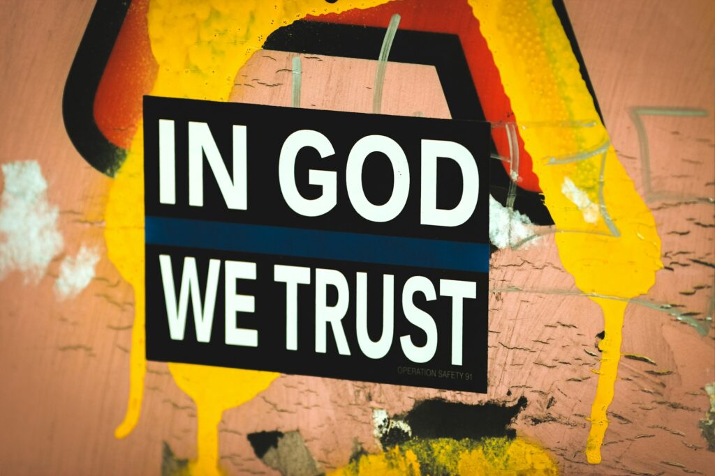 In God We Trust written on a graffitied wall.