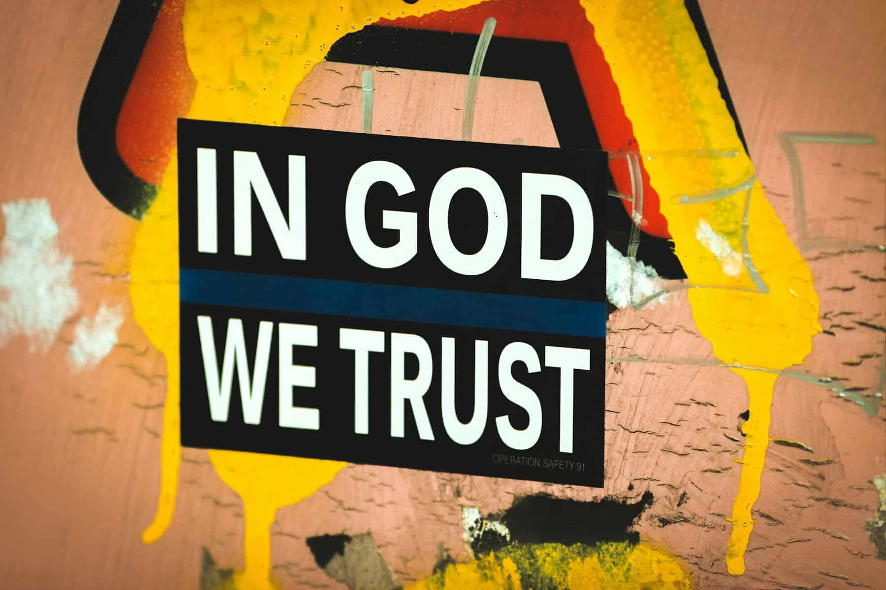In God We Trust written on a graffitied wall.